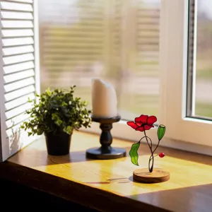 Stained glass poppy flower sun catcher detail reflecting warm natural light on a windowsill