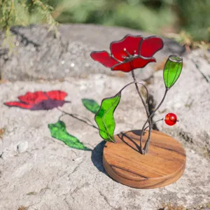 Artistic detail of stained glass poppy flower sun catcher with rustic wooden base