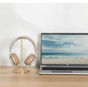 Sleek gold metal headphone stand displayed on a wooden desk with a laptop
