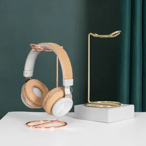 Minimalist metal headphone stand in rose gold and gold finishes for home desk storage