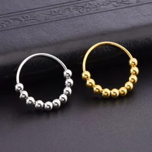Detailansicht von Titanstahlringen mit beweglichen silbernen und goldenen Perlen auf Leder.