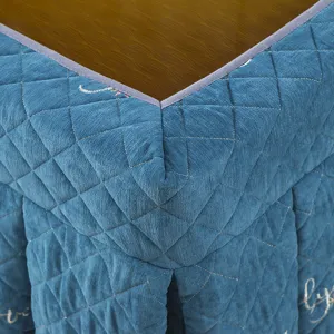 Detailed close-up of thick quilted blue heating table cover fabric with elegant texture.