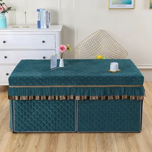 Detail view of dark green quilted rectangular heating table cover with elegant frill and golden trim