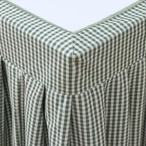 Green and white checkered table cover detail, showing neat pleated fringe and fabric texture.