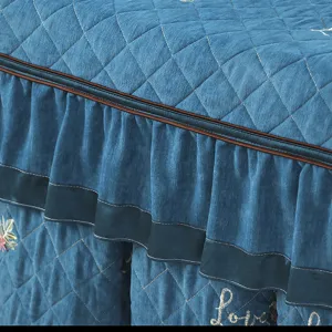 Detailed view of thick quilted blue table cover featuring elegant ruffles and embroidery.