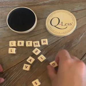 Nahaufnahme des Q-Less Kreuzworträtsel-Solitärspiels mit Holzwürfeln und einer Metalldose