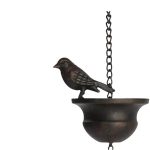 Close-up detail of an antique bronze bird and cup on a garden rain chain hanger.
