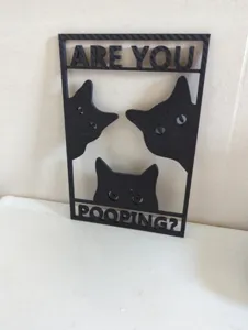Close-up of black cat bathroom sign featuring three curious cats and humorous text