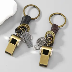 Close-up of vintage brass whistle keychains with black and brown leather straps.