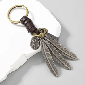 Detailed view of vintage hand-woven leather keychain with alloy feather charms