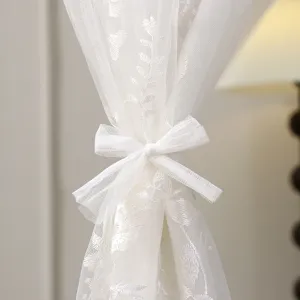 Cortina transparente blanca de encaje con bordado floral y bonito lazo decorativo.