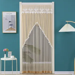 Close-up detail of sheer door curtain with elegant lace embroidery and pompom trim fringe.