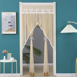 Detailed view of beige lace door curtain with delicate mesh and pom-pom trim for home.