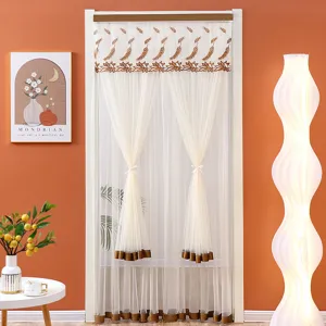 Close-up of white mesh lace door curtain with brown wheat embroidery and neat bow tiebacks.