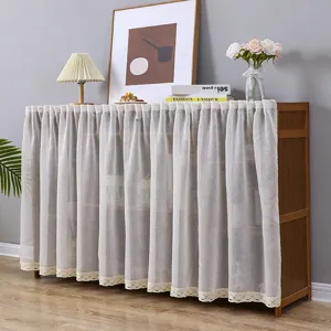 Vista detallada de una cortina antipolvo de encaje blanco en mueble de madera para interior.