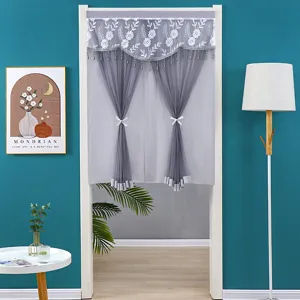 Detailaufnahme des grauen Spitzenvorhangs mit Blumenstickerei, Perlenquasten und hübschen Bändern.