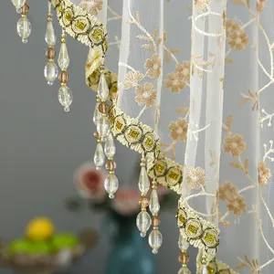 Detailed view of embroidered lace sheer curtain with beaded fringe for elegant home window decor.