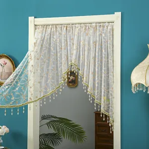 Close-up view of elegant lace door curtain with floral embroidery and hanging crystal bead fringe.