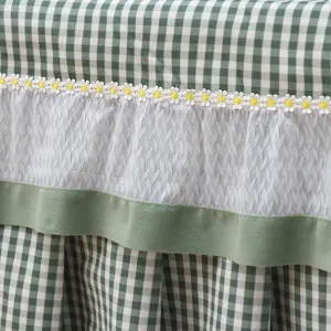 Detailaufnahme der grün-weißen Karo-Tischdecke mit Blumen-Spitzenbesatz und Textilstruktur.