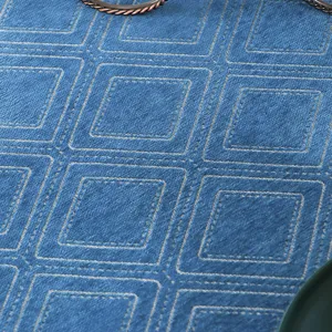 Close-up detail of blue quilted square tablecloth fabric texture, showing fine stitching.