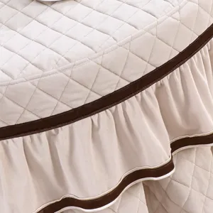 Detailopname van gewatteerde pluche ronde tafelhoes met elegante bruine fluwelen afwerking.