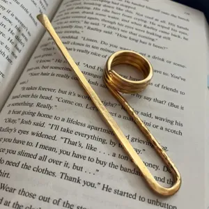 Segnalibro ad anello in metallo dorato martellato su pagine di un libro aperto.