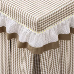 Detail view of brown plaid table cover with white lace and daisy embroidery for square table.