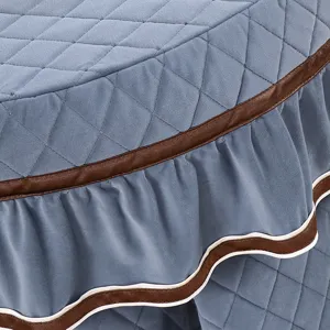 Gedetailleerde close-up van gewatteerde ronde tafelhoes met elegante bruine rand.