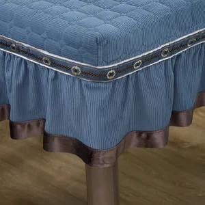 Detailansicht des gesteppten blauen Stuhlkissenbezugs mit bestickter Spitze und braunem Saum.