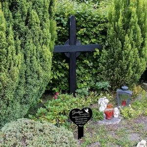 Schwarzer herzförmiger Gedenkstecker mit Beileidsspruch in einem Garten im Freien