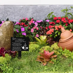 Detailansicht eines schwarzen Garten-Gedenkpfahls mit Kreuz und Tauben im Garten
