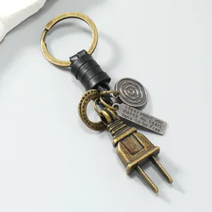 Detailed macro view of a vintage alloy plug keychain featuring a black leather braid and charms
