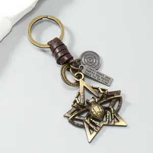 Macro detail of retro metal spider pentagram keychain with brown leather braided cord