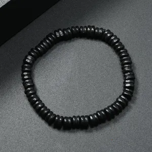 Vista macro detallada de una pulsera de cuentas de madera negra sobre fondo rugoso