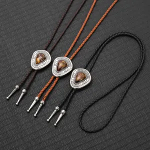 Detailansicht von Retro-Leder-Bolo-Krawatten mit Metallanhängern und Steinen.