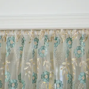 Detailed view of French vintage lace short curtain with teal floral embroidery and gold leaves.