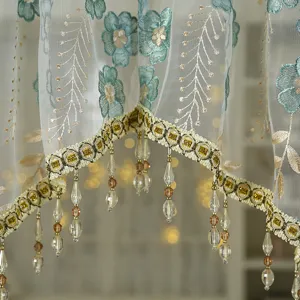 Detailed view of a French vintage lace short curtain with blue embroidery and gold crystal fringe.