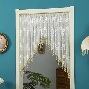 White lace door curtain detail showcasing delicate floral embroidery and elegant beaded fringe trim.