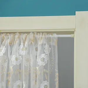 Detailed view of white lace floral sheer curtain hanging on rod for bedroom home decoration.