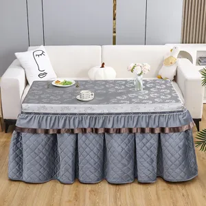 Close-up detail of grey quilted heating table cover with elegant ruffles, cozy living room.