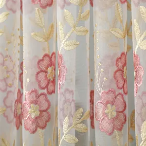 Detailed view of sheer curtain with pink floral embroidery and gold leaves for home decor.