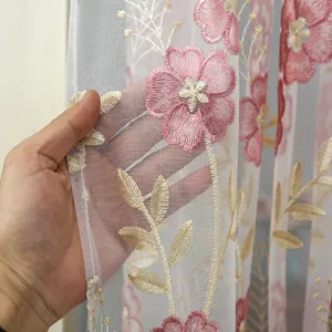 Close-up view of sheer lace curtain fabric showcasing delicate pink floral embroidery details.