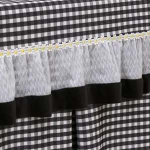 Black and white grid table cover detail with delicate lace daisy ruffle, modern textile decor.