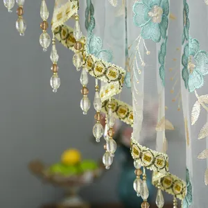 Close-up detail of Korean style lace half curtain with blue embroidery, gold trim and bead fringe.