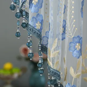 Detailed shot of Korean style lace half curtain with blue floral embroidery and beaded fringe.