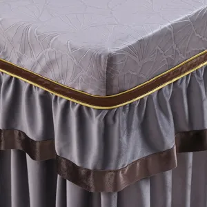 Detailansicht der grauen Tischabdeckung mit gepraegtem Ginkgo-Muster und braunem Samtbesatz.