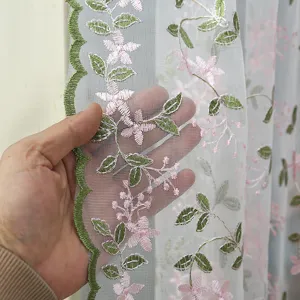 Close-up detail of sheer curtain fabric with pink floral embroidery, sheer mesh texture.
