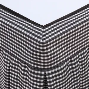 Close-up detail of black and white gingham checkered table cover fabric and pleated skirt edge.