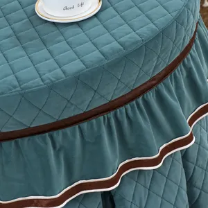 Verdikte gewatteerde ronde kotatsu tafelhoes met volant en bruine rand detailweergave.