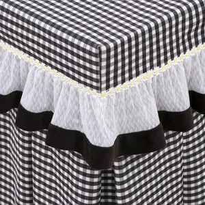 Detailed close-up of black and white checkered fabric table cover with white lace ruffle trim.